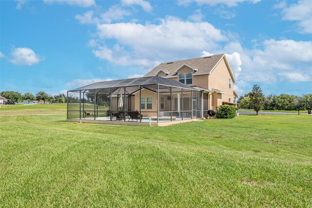 back of house featuring glass enclosure, a yard, a patio area, and stucco siding