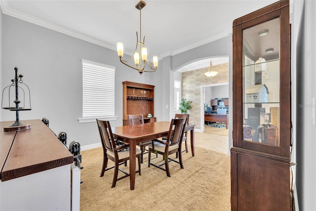 dining area featuring light carpet, arched walkways, baseboards, an inviting chandelier, and ornamental molding