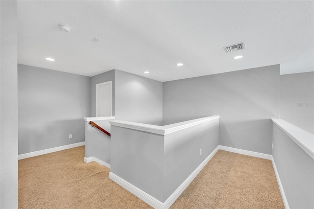 hallway with recessed lighting, carpet floors, visible vents, and an upstairs landing