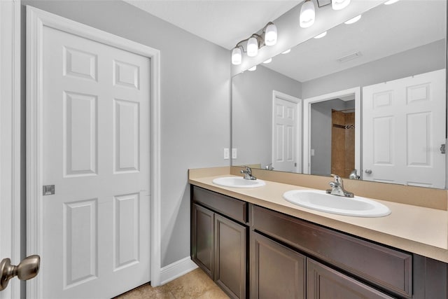 full bath featuring baseboards, a sink, visible vents, and double vanity