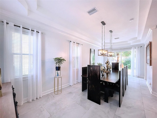 tiled dining room with ornamental molding and a tray ceiling