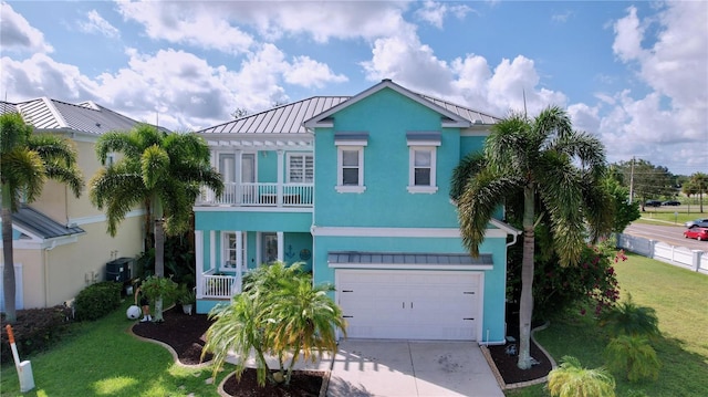 coastal home featuring a garage, a balcony, a front lawn, and central AC unit