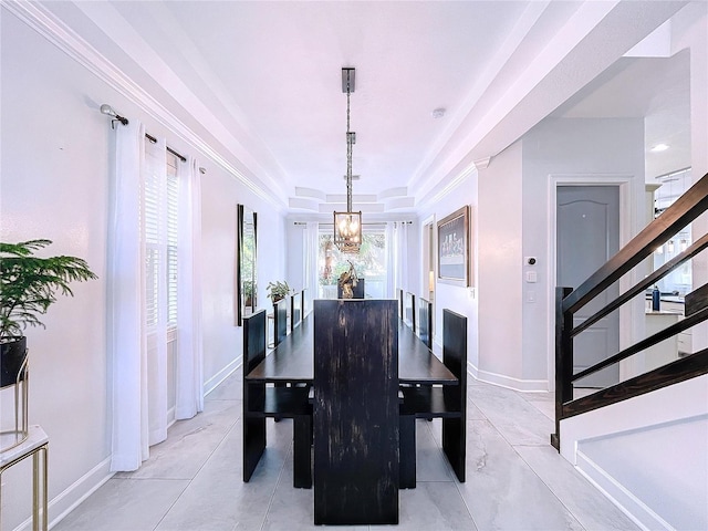 tiled dining area featuring a raised ceiling, crown molding, and an inviting chandelier