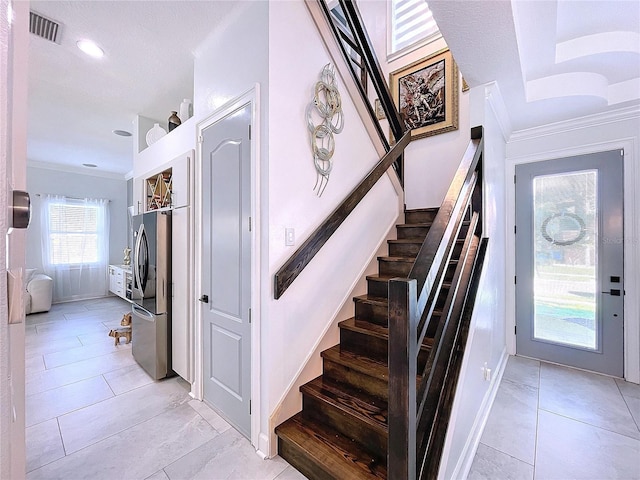 stairs with ornamental molding and tile patterned floors