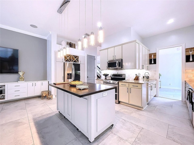 kitchen with white cabinetry, decorative light fixtures, appliances with stainless steel finishes, and a kitchen island