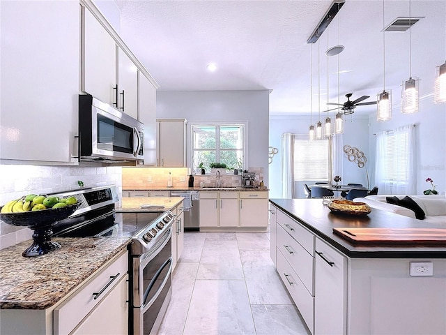 kitchen featuring white cabinets, appliances with stainless steel finishes, hanging light fixtures, and a kitchen island