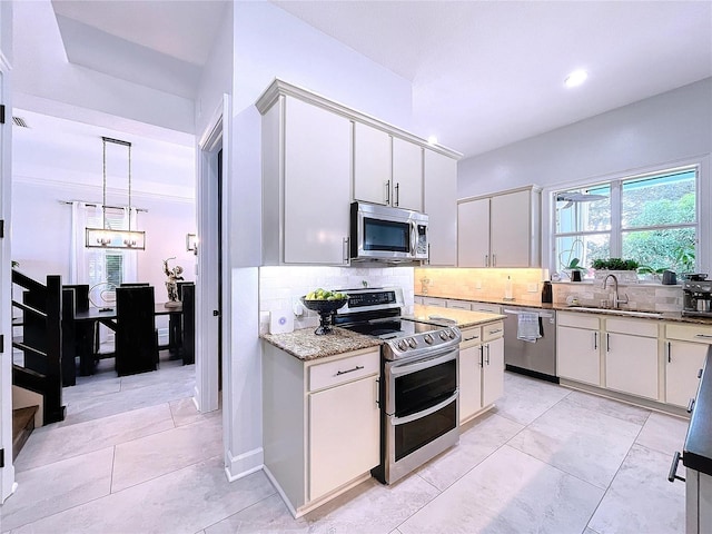 kitchen with stainless steel appliances, hanging light fixtures, sink, and white cabinetry