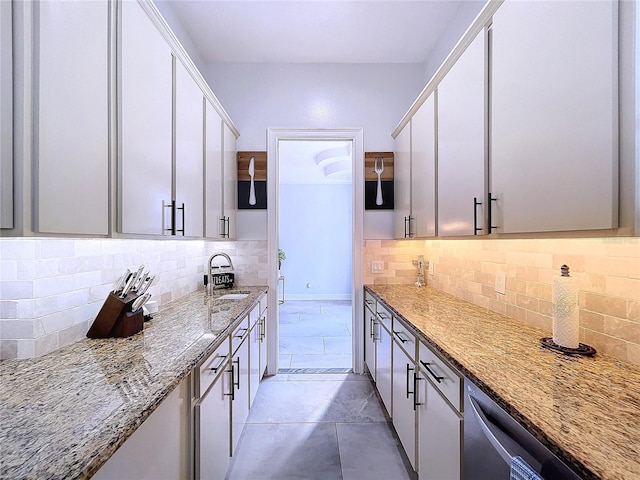 kitchen featuring decorative backsplash, white cabinetry, dishwasher, light stone countertops, and sink