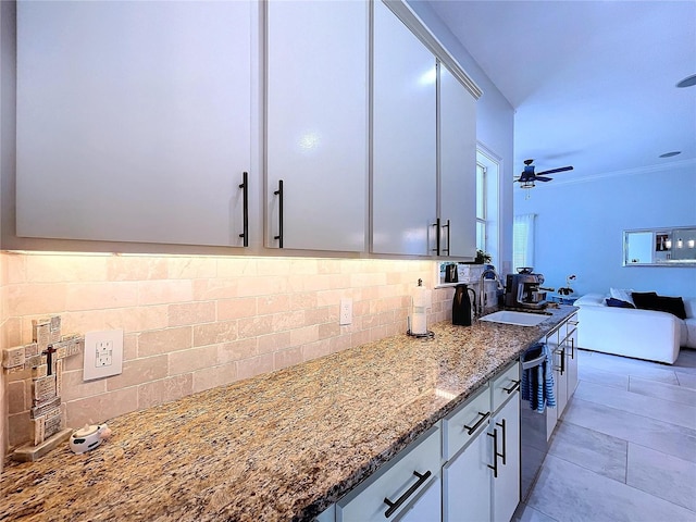 kitchen with dishwasher, sink, stone counters, backsplash, and ceiling fan