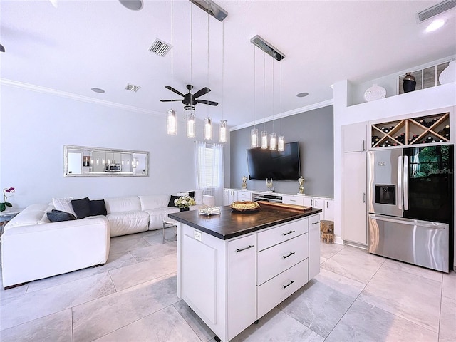 kitchen featuring hanging light fixtures, a kitchen island, stainless steel fridge, and white cabinetry