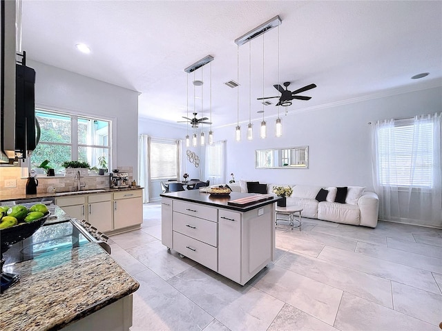 kitchen featuring white cabinetry, crown molding, a center island, decorative light fixtures, and sink