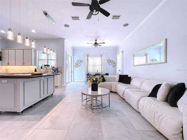 living room with a healthy amount of sunlight, light tile patterned floors, crown molding, and ceiling fan