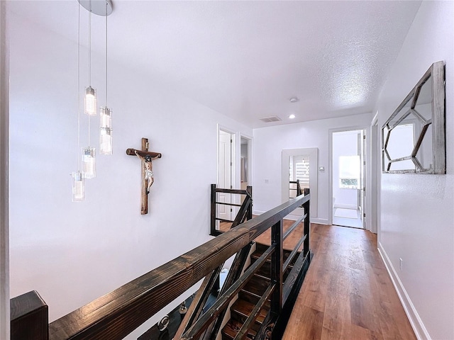 hall with wood-type flooring and a textured ceiling