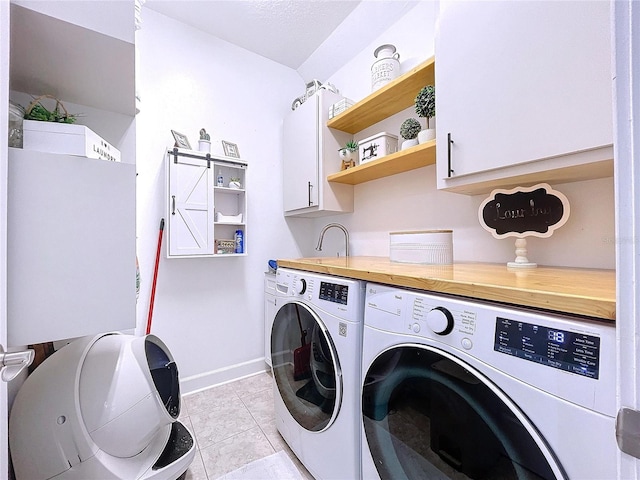 laundry area featuring light tile patterned floors, cabinets, a barn door, and washing machine and dryer