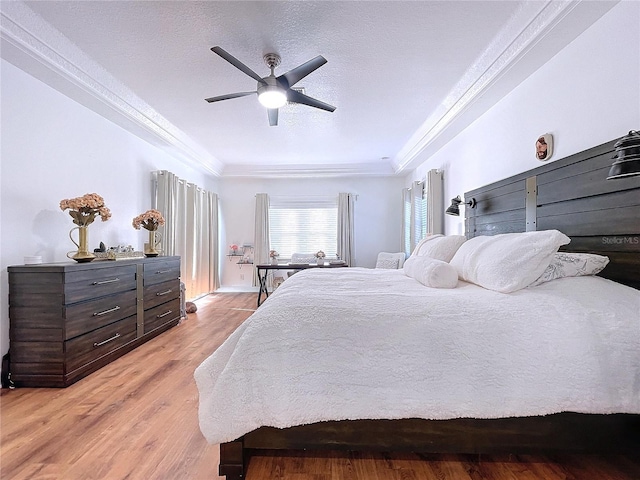 bedroom featuring ceiling fan, ornamental molding, a textured ceiling, and light hardwood / wood-style floors