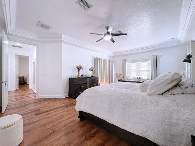 bedroom featuring ornamental molding, ceiling fan, hardwood / wood-style flooring, and a textured ceiling