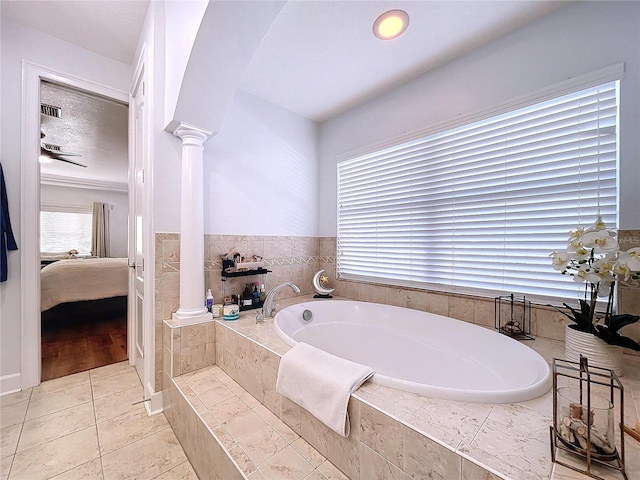 bathroom featuring tile patterned flooring, tiled tub, and ornate columns