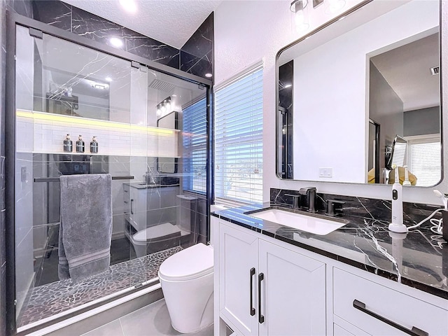 bathroom with vanity, walk in shower, a textured ceiling, tile patterned flooring, and toilet