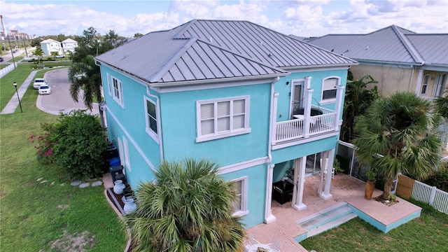 back of house featuring a balcony, a lawn, and a patio area