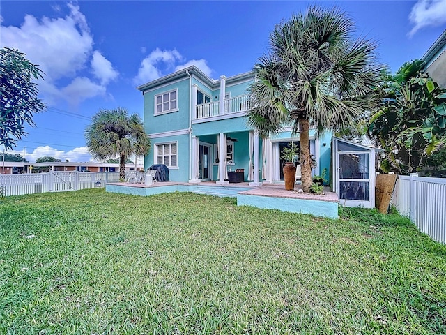 rear view of property with a balcony and a lawn