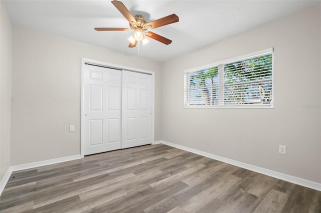 unfurnished bedroom featuring a closet, hardwood / wood-style flooring, and ceiling fan