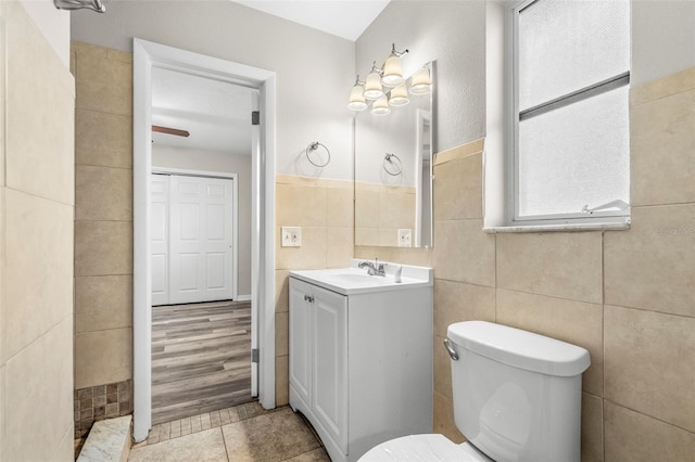 bathroom with hardwood / wood-style floors, vanity, tile walls, and toilet