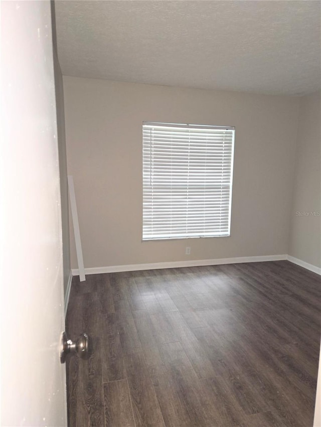 unfurnished room with a textured ceiling and dark hardwood / wood-style flooring