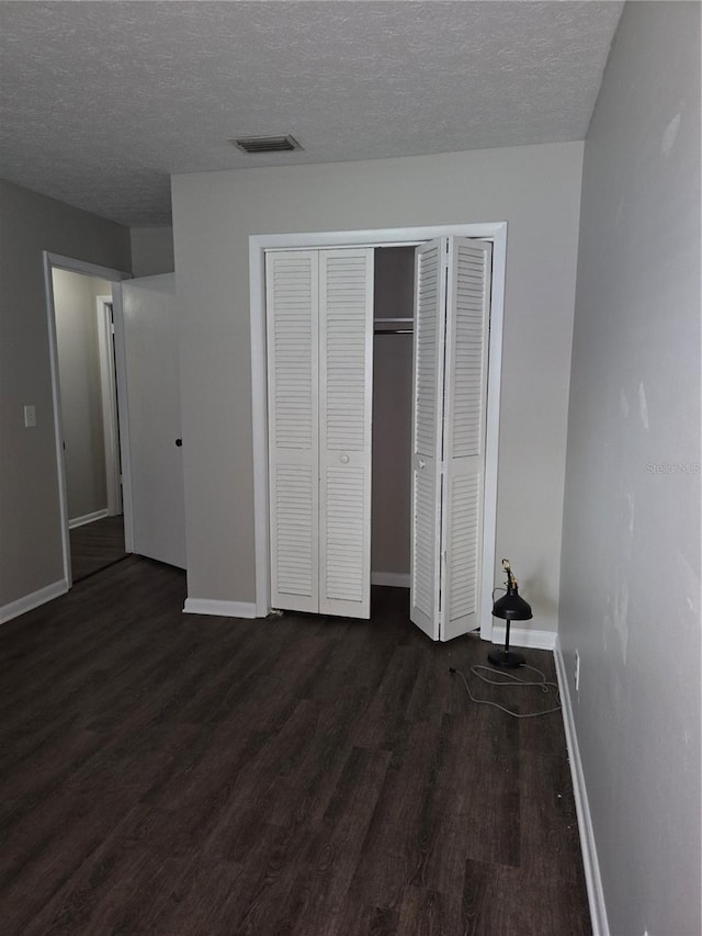 unfurnished bedroom featuring a textured ceiling and dark hardwood / wood-style flooring