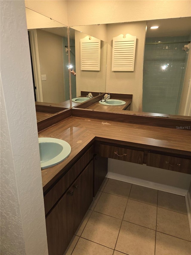 bathroom featuring tiled shower, vanity, and tile patterned flooring