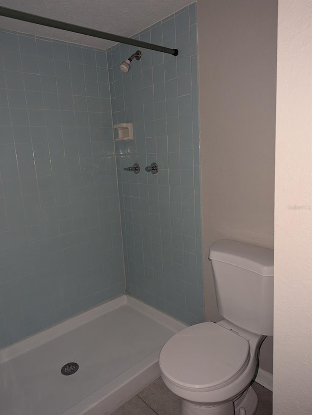 bathroom with a tile shower, tile patterned flooring, and toilet