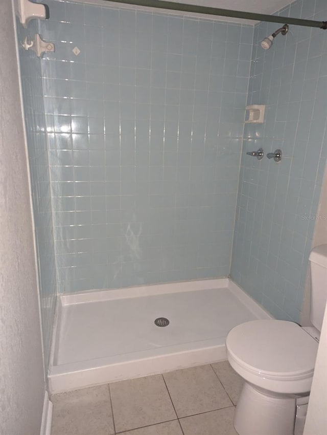 bathroom with a tile shower, tile patterned floors, and toilet