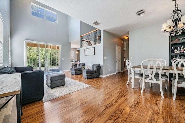 living room featuring a textured ceiling, a high ceiling, hardwood / wood-style floors, and a notable chandelier