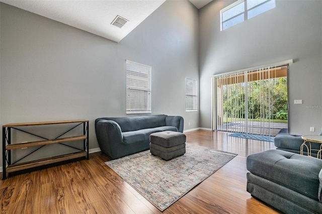 living room with a towering ceiling, hardwood / wood-style flooring, and a healthy amount of sunlight