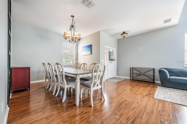 dining space with a chandelier, a textured ceiling, and hardwood / wood-style floors