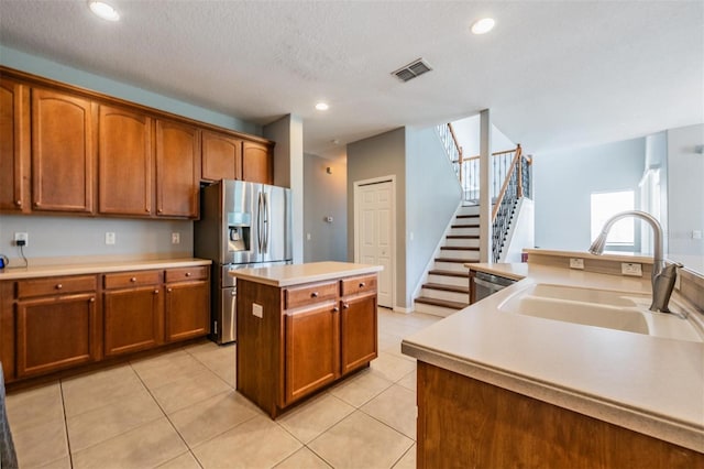 kitchen with light tile patterned floors, sink, a kitchen island with sink, and stainless steel appliances