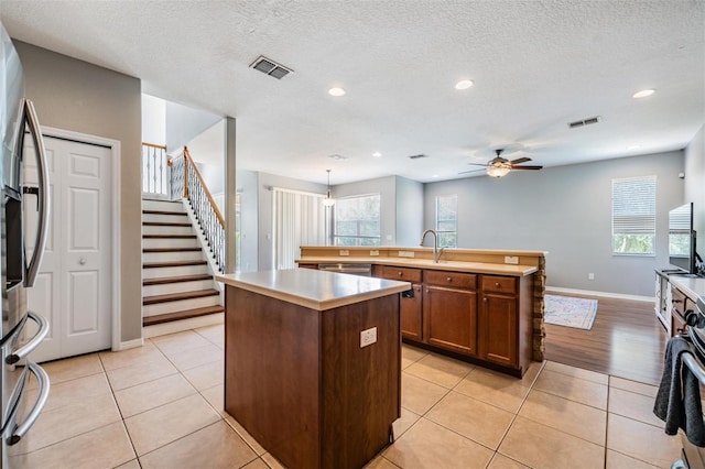 kitchen featuring light tile patterned flooring, a kitchen island with sink, and decorative light fixtures