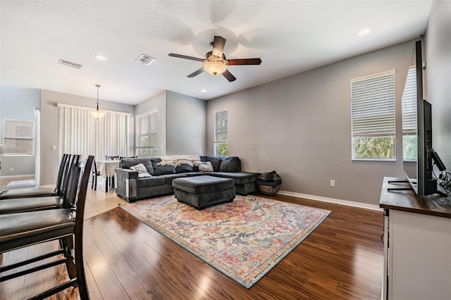 living room with ceiling fan, plenty of natural light, and dark hardwood / wood-style flooring