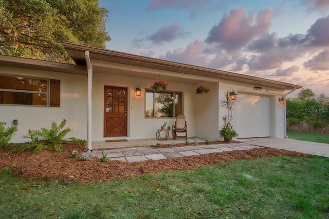 view of front of house featuring a garage, a lawn, and covered porch