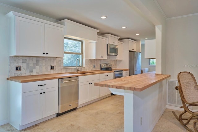 kitchen featuring a wealth of natural light, white cabinetry, butcher block counters, sink, and stainless steel appliances