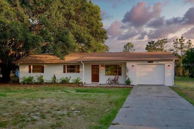 single story home featuring a garage and a yard