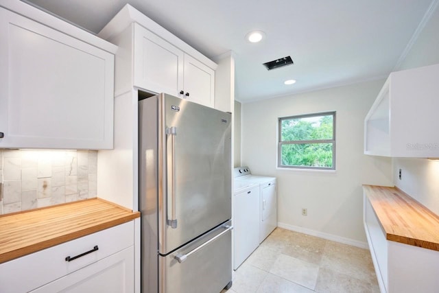 kitchen with washing machine and clothes dryer, wooden counters, high end fridge, and white cabinets