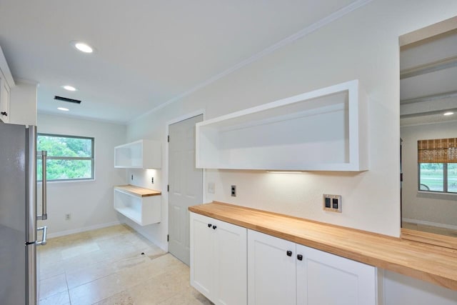 kitchen featuring white cabinets, crown molding, wooden counters, and stainless steel refrigerator