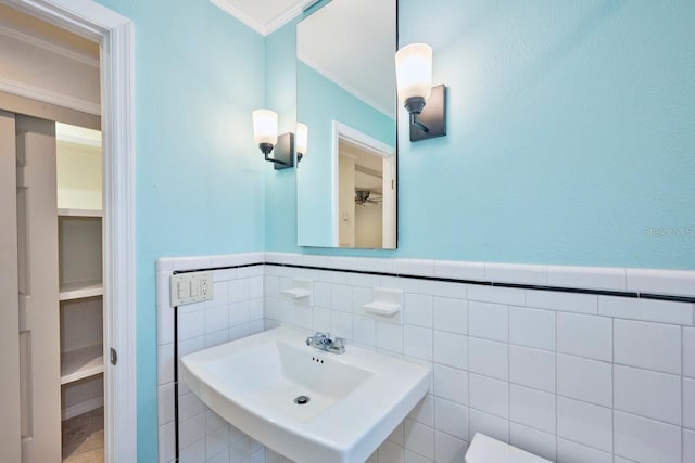 bathroom with tile walls, sink, and crown molding