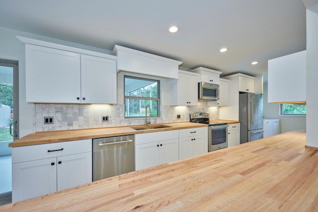 kitchen with wood counters, sink, backsplash, white cabinets, and stainless steel appliances