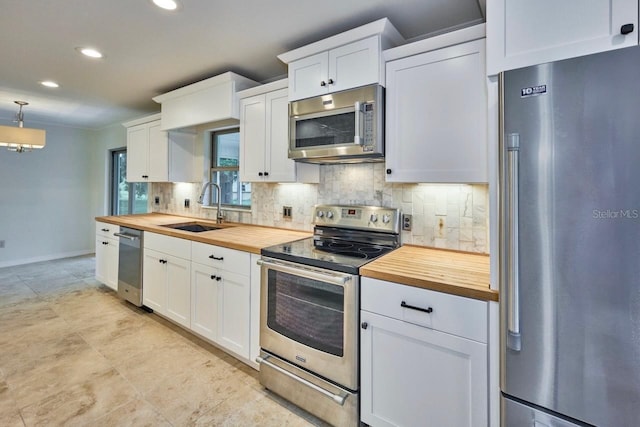 kitchen featuring a sink, white cabinetry, stainless steel appliances, butcher block counters, and decorative backsplash