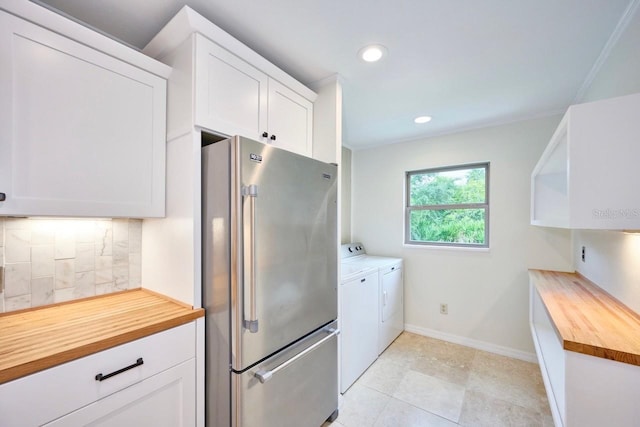 kitchen with backsplash, wooden counters, washing machine and dryer, high end refrigerator, and white cabinetry