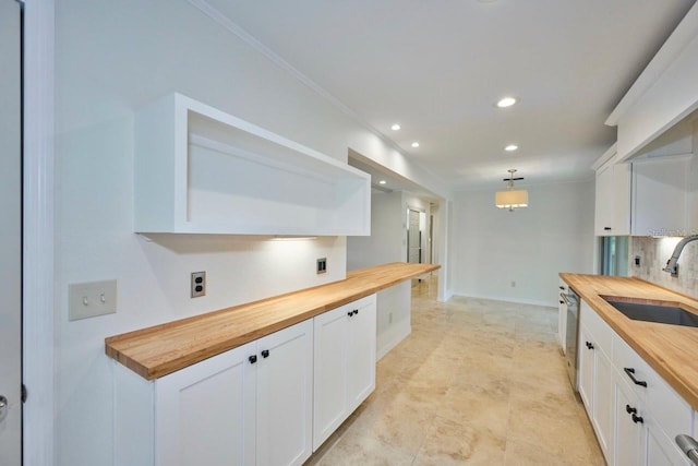 kitchen featuring wooden counters, a sink, white cabinets, stainless steel dishwasher, and tasteful backsplash