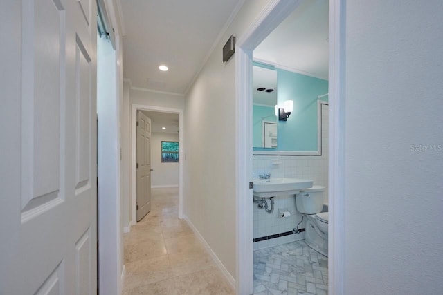 hallway featuring light tile patterned floors, tile walls, crown molding, and a barn door