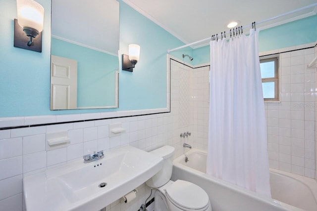 full bathroom featuring toilet, wainscoting, shower / tub combo, tile walls, and a sink