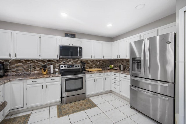 kitchen with dark stone counters, white cabinetry, decorative backsplash, stainless steel appliances, and light tile patterned floors